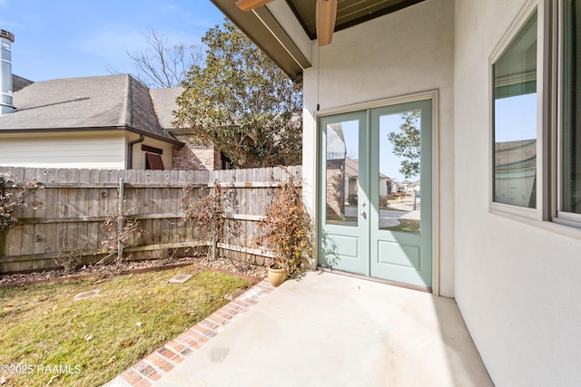 view of exterior entry with a patio, a lawn, and french doors