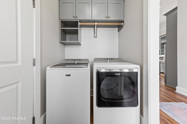 laundry room featuring dark wood-type flooring, cabinets, and washing machine and clothes dryer