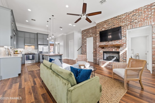 living room with crown molding, a fireplace, dark hardwood / wood-style floors, and ceiling fan