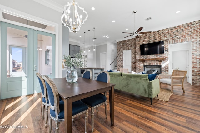 dining area with a fireplace, brick wall, dark hardwood / wood-style flooring, and ornamental molding