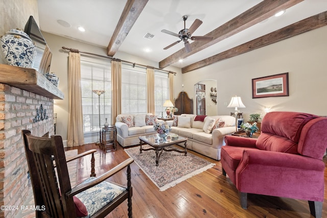 living room with ceiling fan, a fireplace, beam ceiling, and light hardwood / wood-style flooring