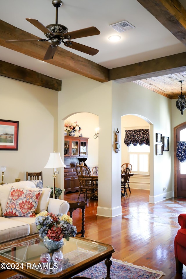 living room featuring ceiling fan, light hardwood / wood-style floors, and beamed ceiling