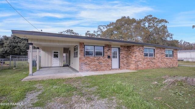 rear view of property with a carport, a yard, and a patio