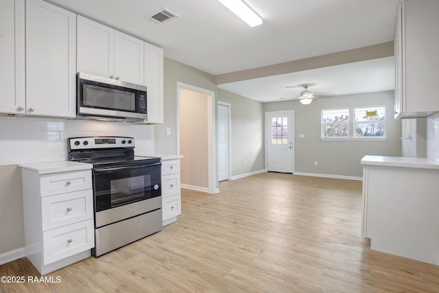 kitchen featuring white cabinetry, appliances with stainless steel finishes, ceiling fan, light hardwood / wood-style floors, and backsplash