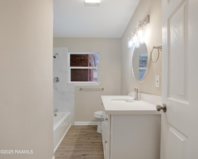 full bathroom with tiled shower / bath combo, vanity, hardwood / wood-style floors, and toilet