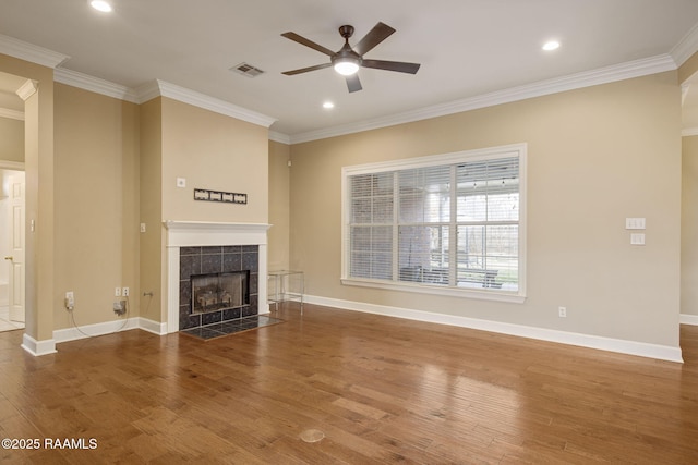 unfurnished living room featuring hardwood / wood-style flooring, ceiling fan, crown molding, and a tile fireplace