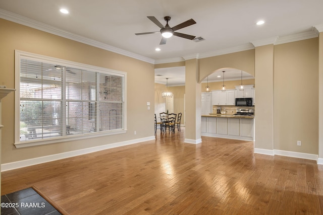 unfurnished living room featuring ceiling fan with notable chandelier, light hardwood / wood-style flooring, and ornamental molding