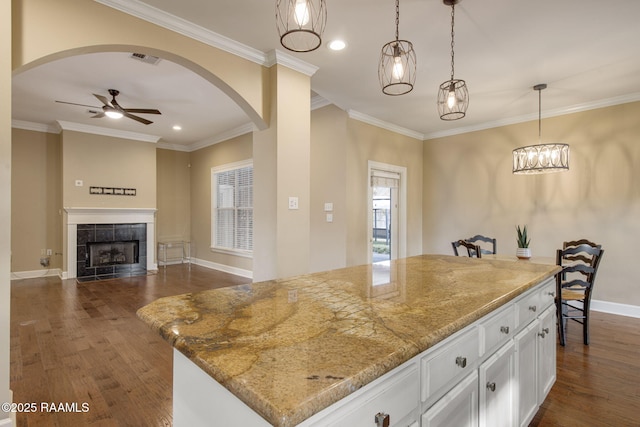 kitchen featuring pendant lighting, white cabinetry, a center island, a fireplace, and dark hardwood / wood-style flooring