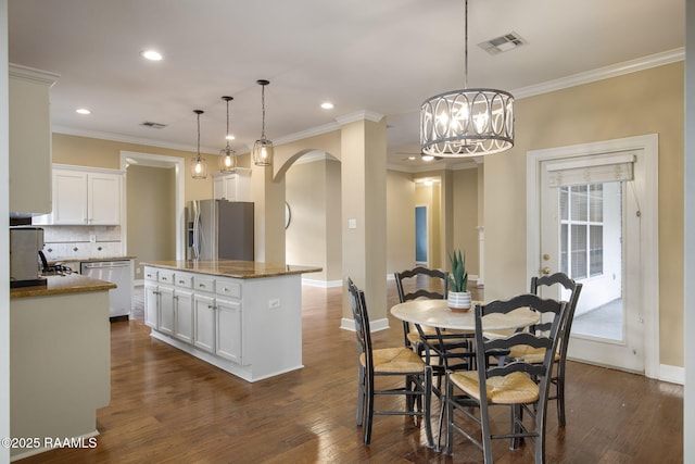 kitchen featuring decorative light fixtures, appliances with stainless steel finishes, white cabinets, and a kitchen island