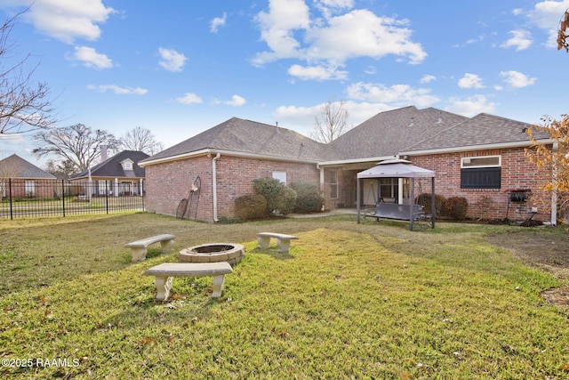 rear view of house with a gazebo, a lawn, and an outdoor fire pit