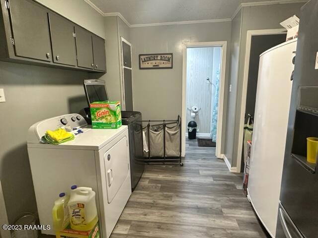 laundry area with cabinets, ornamental molding, dark hardwood / wood-style flooring, and washing machine and dryer