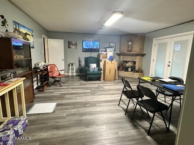 dining space with wood-type flooring, a fireplace, and french doors