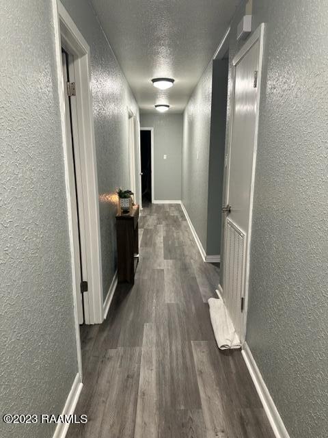 hallway with dark wood-type flooring and a textured ceiling