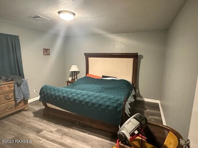 bedroom with hardwood / wood-style flooring and a textured ceiling