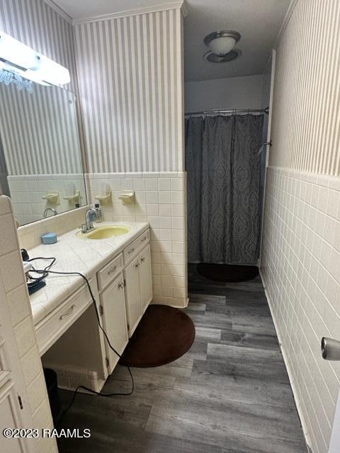 bathroom featuring crown molding, wood-type flooring, tile walls, and vanity