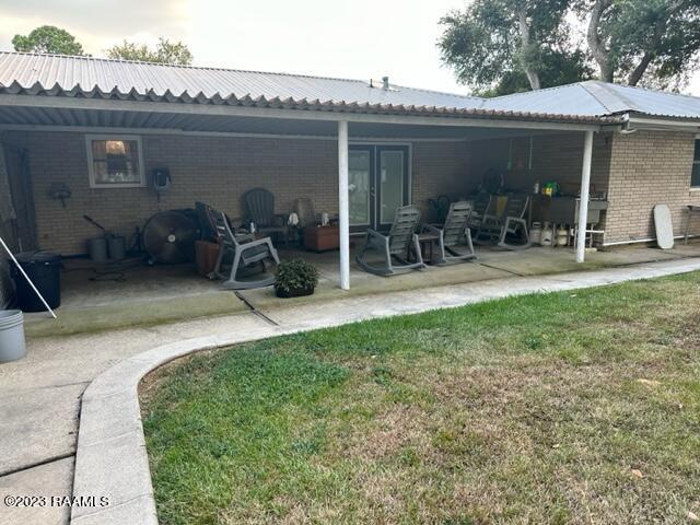 back of house with a patio and a lawn