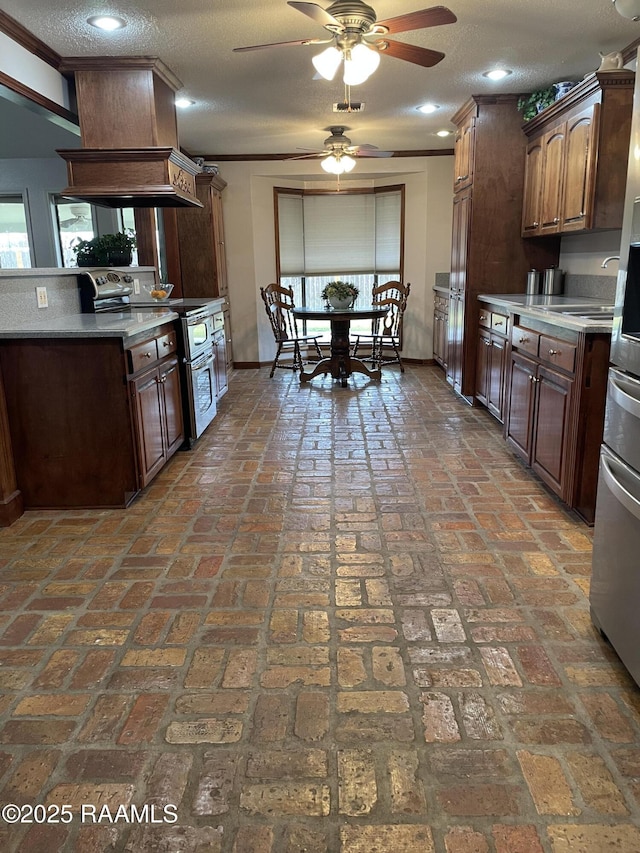 kitchen featuring ceiling fan, appliances with stainless steel finishes, custom range hood, and a textured ceiling