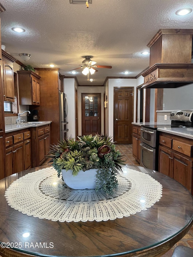 kitchen with sink, custom exhaust hood, stainless steel appliances, crown molding, and a textured ceiling