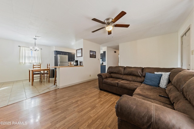 living room featuring wood-type flooring and ceiling fan with notable chandelier