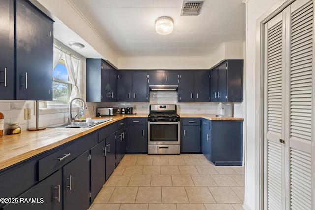 kitchen featuring light tile patterned flooring, sink, stainless steel gas range oven, tasteful backsplash, and wooden counters