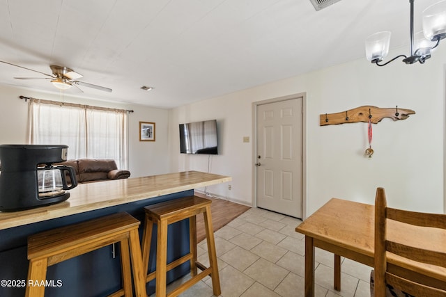 kitchen featuring ceiling fan with notable chandelier, pendant lighting, light tile patterned floors, and a kitchen breakfast bar