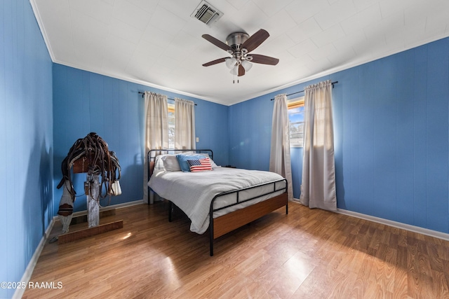 bedroom with wood-type flooring, ornamental molding, and ceiling fan