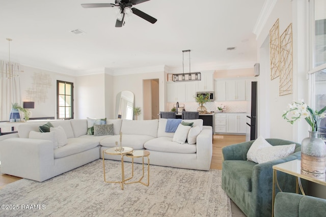 living room with ceiling fan, ornamental molding, and light wood-type flooring