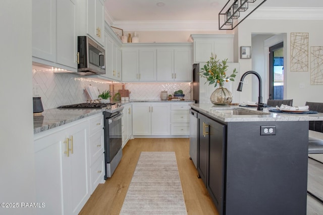 kitchen with white cabinetry, stainless steel appliances, sink, and an island with sink