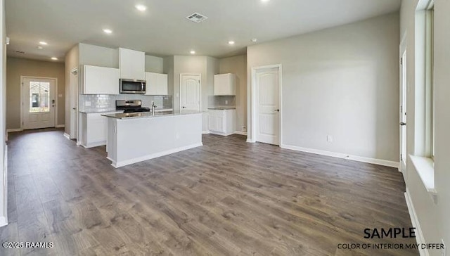 kitchen with white cabinetry, tasteful backsplash, an island with sink, hardwood / wood-style flooring, and stainless steel appliances