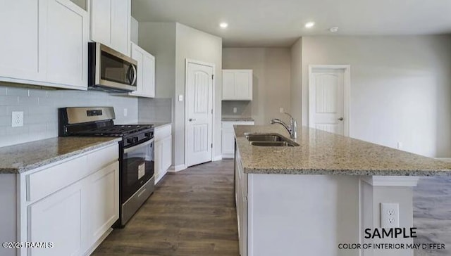 kitchen featuring an island with sink, sink, white cabinets, stainless steel appliances, and light stone countertops