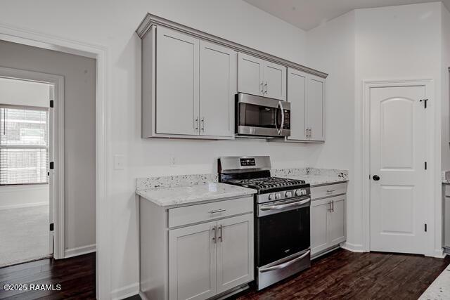 kitchen with light stone counters, stainless steel appliances, and dark hardwood / wood-style floors