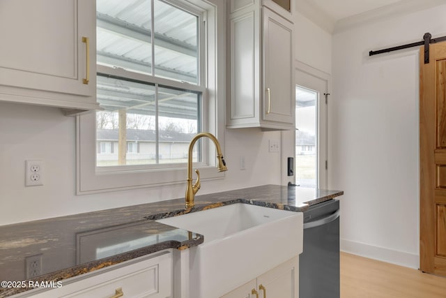 kitchen featuring a barn door, dishwasher, sink, and white cabinets