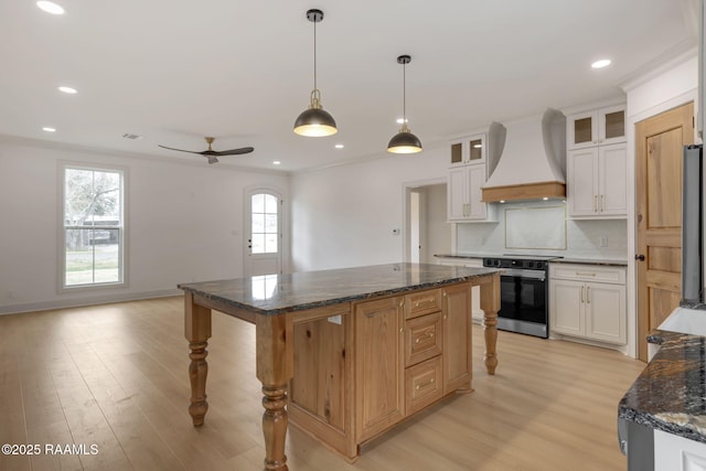 kitchen featuring white cabinets, stainless steel range with electric stovetop, custom exhaust hood, a center island, and light hardwood / wood-style floors