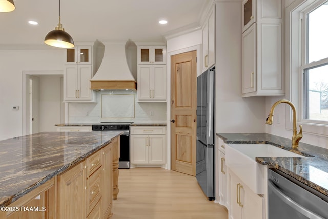 kitchen featuring premium range hood, appliances with stainless steel finishes, pendant lighting, white cabinets, and dark stone counters