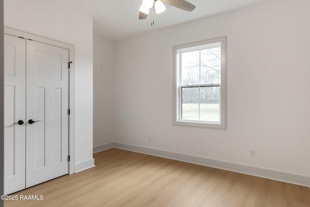 unfurnished bedroom with multiple windows, ceiling fan, light wood-type flooring, and a closet