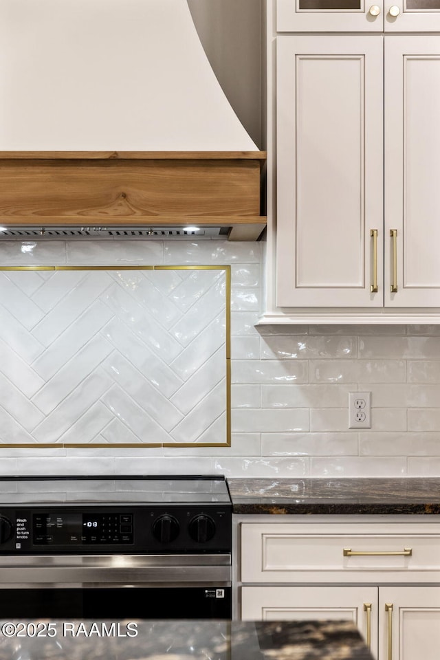 kitchen featuring stove, decorative backsplash, and white cabinets