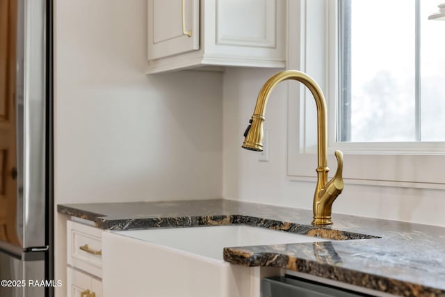 interior details with white cabinetry, sink, stainless steel appliances, and dark stone countertops