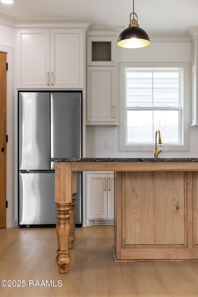 kitchen featuring stainless steel refrigerator, dark stone countertops, and white cabinets