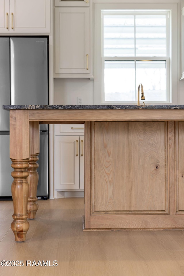 kitchen with stainless steel refrigerator, dark stone counters, and sink