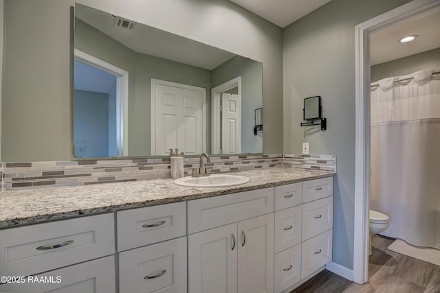 bathroom with hardwood / wood-style floors, vanity, toilet, and decorative backsplash