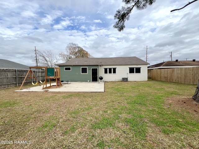 rear view of house with a playground, a patio, central air condition unit, and a lawn