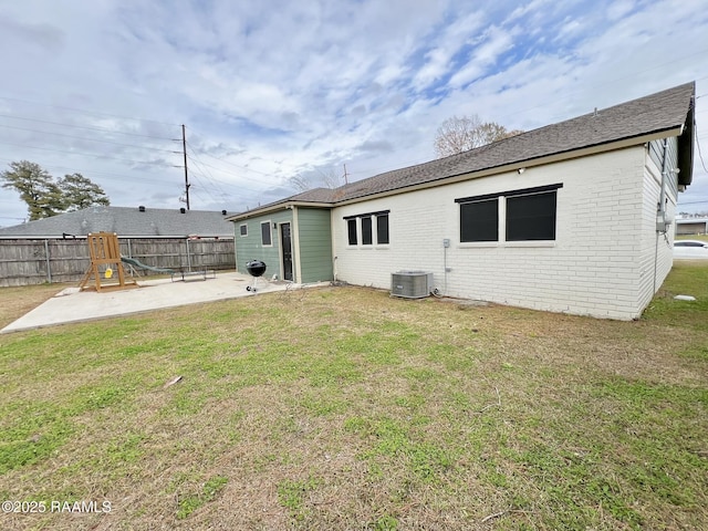 back of house with a playground, central air condition unit, a patio area, and a lawn