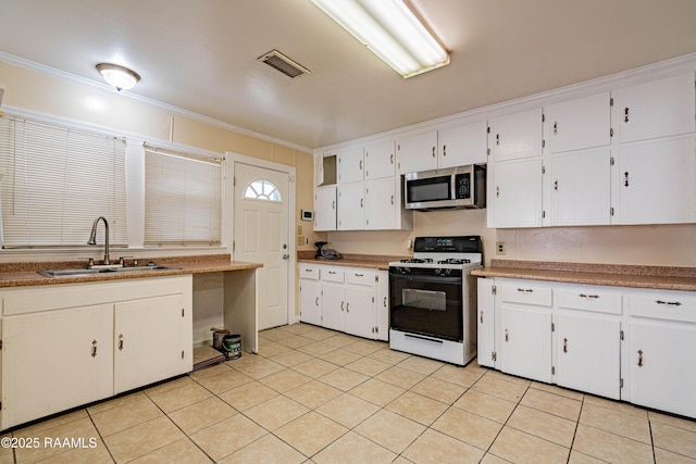 kitchen with range with gas stovetop, sink, white cabinets, light tile patterned floors, and crown molding