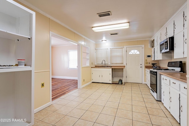 kitchen with sink, gas stove, and white cabinets