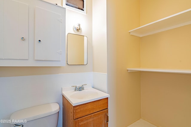 bathroom featuring vanity, tile walls, and toilet