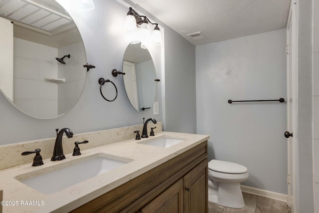 bathroom featuring vanity, a textured ceiling, tile patterned floors, and toilet