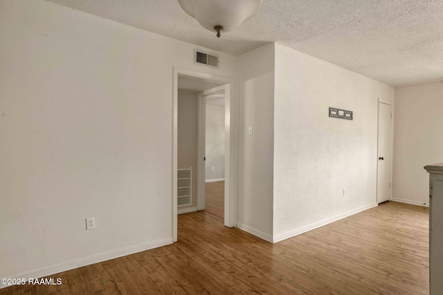 spare room with a textured ceiling and light hardwood / wood-style floors