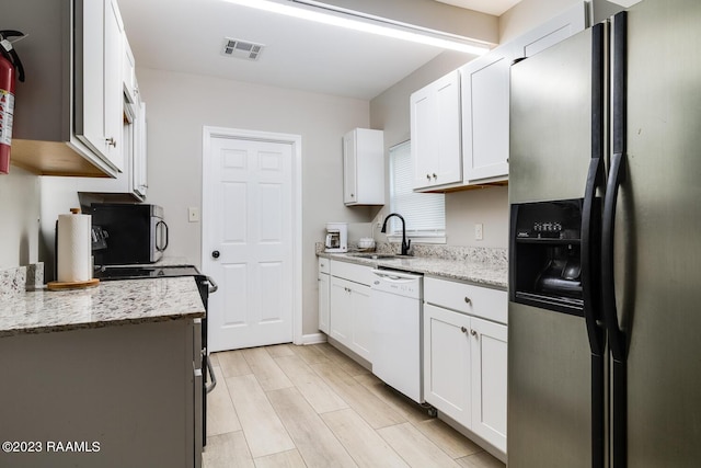 kitchen featuring sink, white cabinetry, light stone counters, light hardwood / wood-style flooring, and appliances with stainless steel finishes