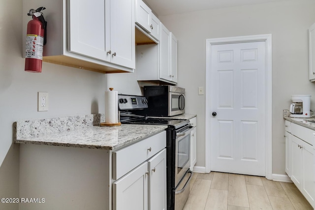 kitchen featuring light stone countertops, white cabinetry, and appliances with stainless steel finishes