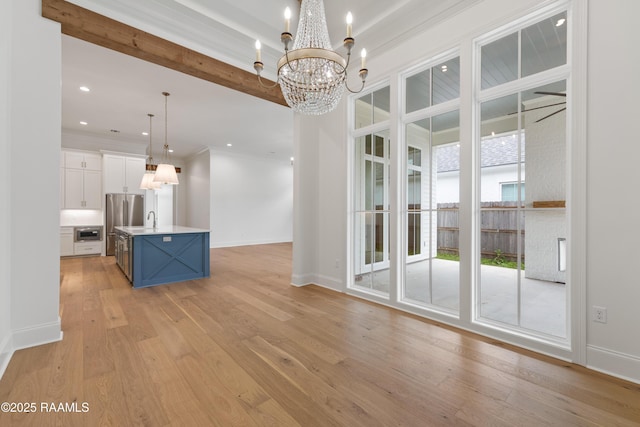 interior space with a notable chandelier, ornamental molding, a healthy amount of sunlight, and light wood-type flooring